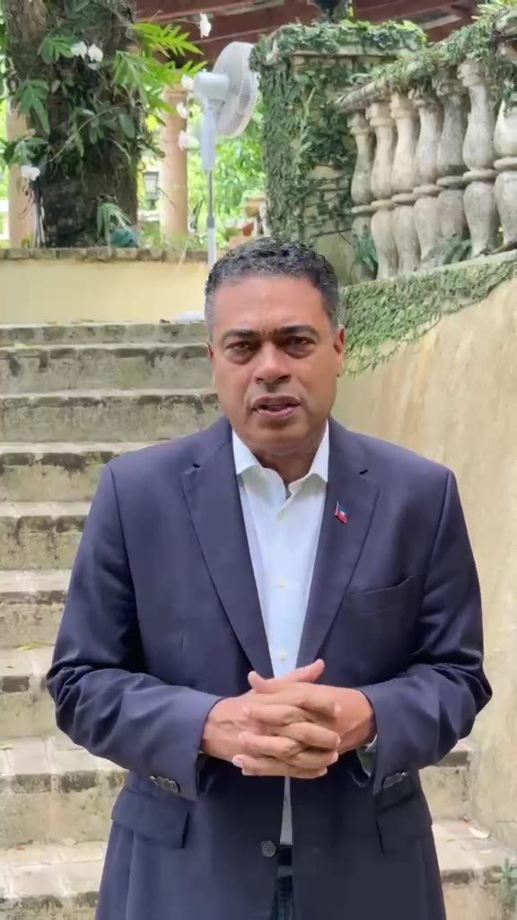 Jerry Tardieu s'exprimant en extérieur, dans un jardin, à propos du vote de la diaspora haïtienne.