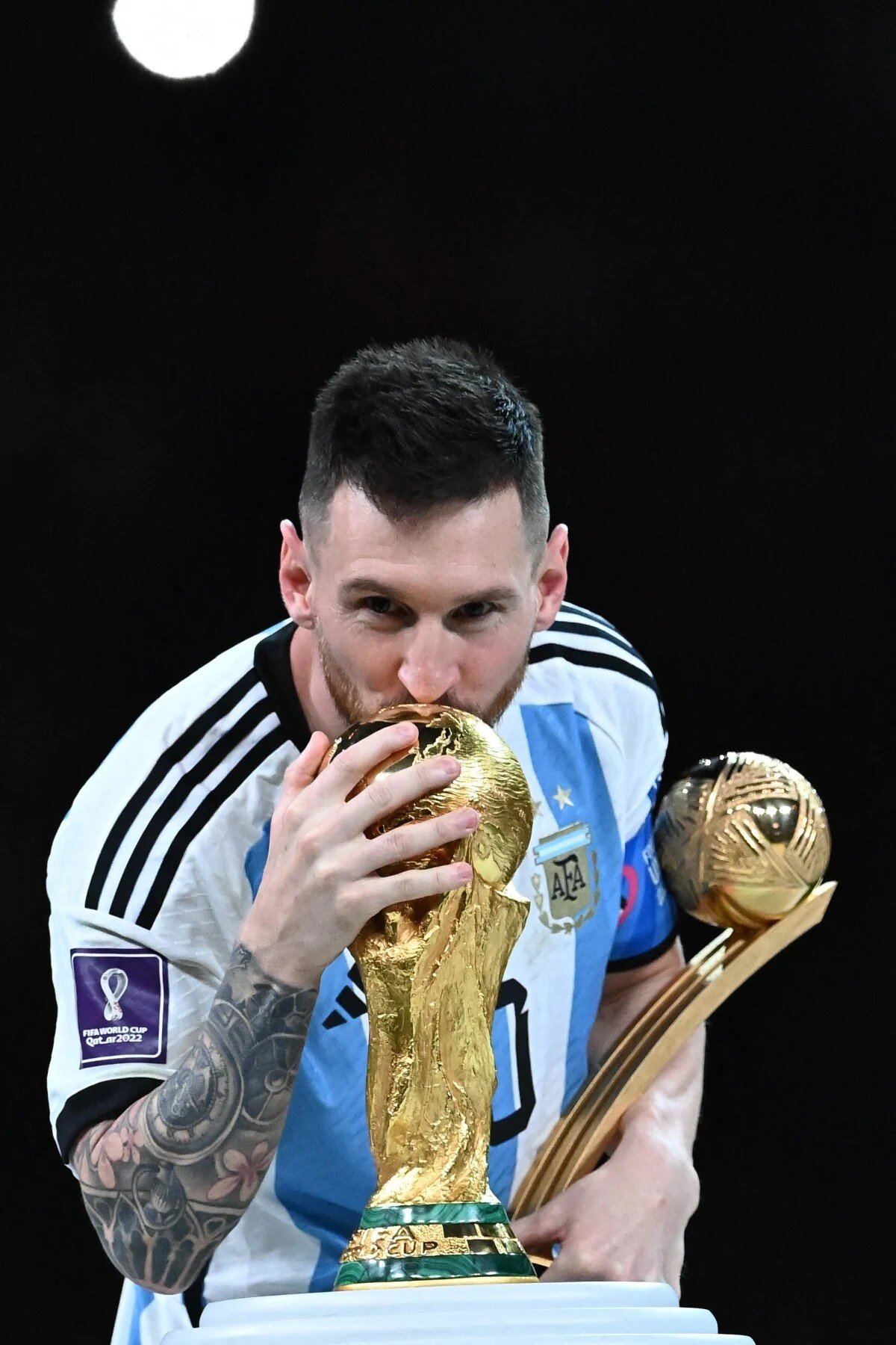Lionel Messi embrassant le trophée de la Coupe du monde, en maillot de l'Argentine.