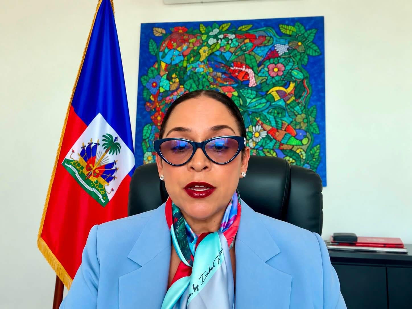 La ministre haïtienne des Affaires étrangères et des Cultes, Raina Forbin, s'exprime en visioconférence devant le drapeau et les armoiries d'Haïti.