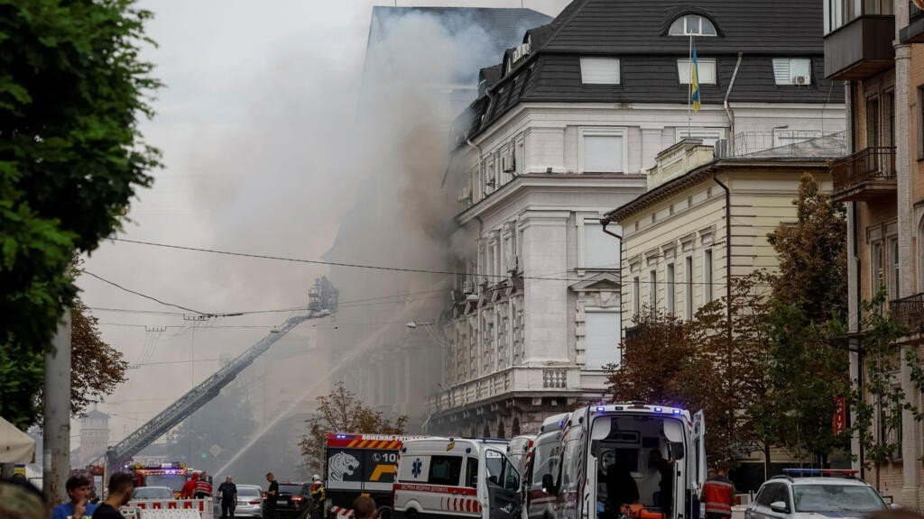Pompiers et véhicules de secours devant un immeuble en feu à Kyiv après une frappe de drone russe.